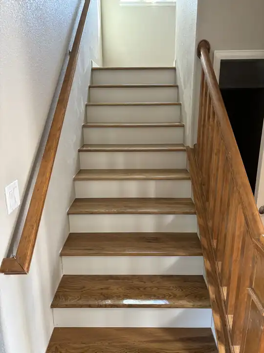 Interior staircase with refinished wood treads and a stained handrail