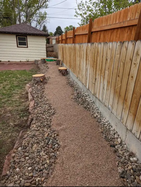 Gravel path running along a cedar fence