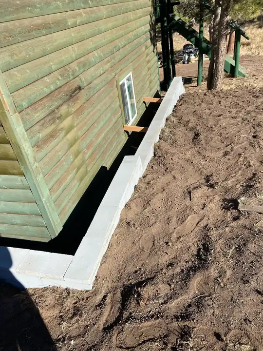 New concrete footing along green siding