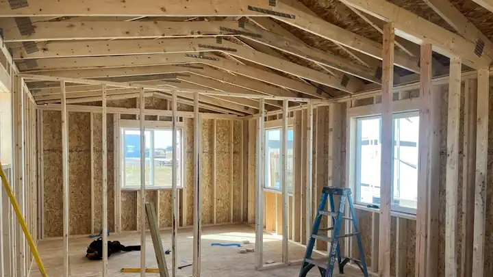 New interior framing with roof trusses and window openings, ladder in the room