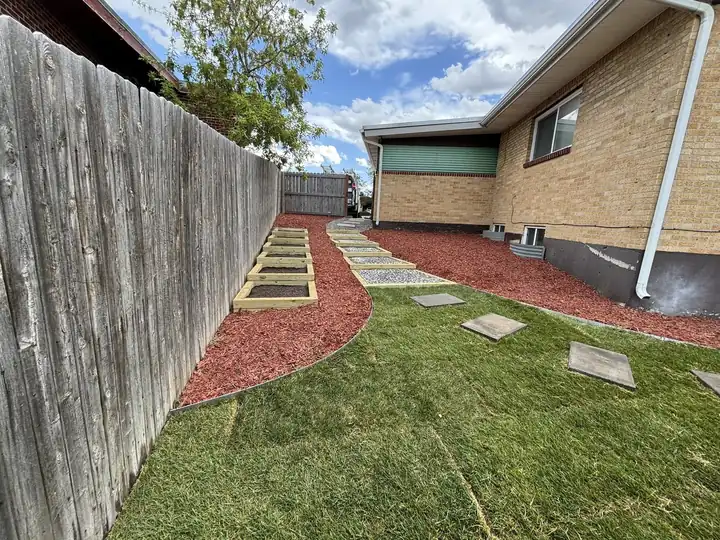 Side yard with sod, red mulch and stepping stones