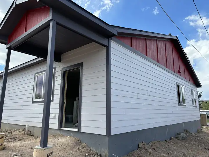 New gray and white siding with a red accent and covered porch